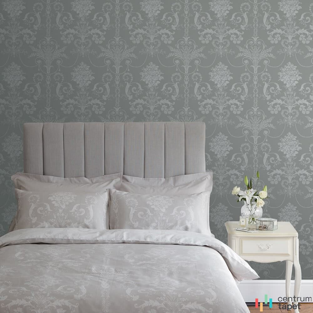 Laura Ashley 113383 za łóżkiem z wysokim szarym zagłówkiem i jasną pościelą