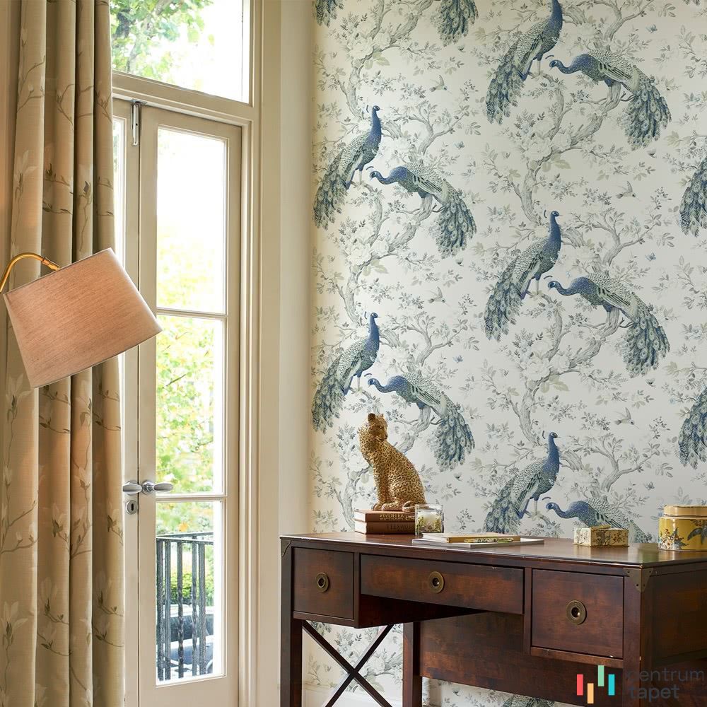 Laura Ashley 113397 za drewnianym stołem do pracy i złotą figurką przy oknie