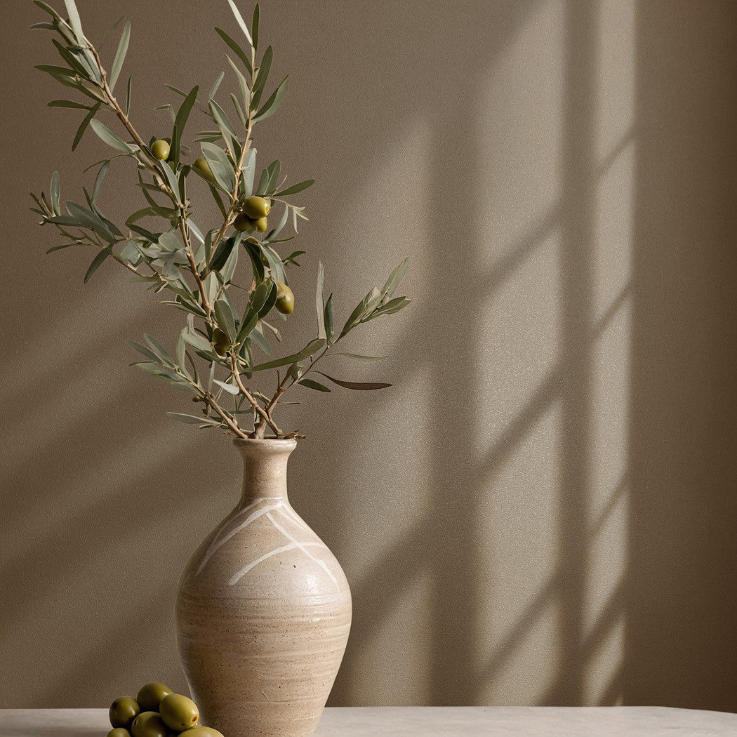 Tapeta Naomi 82533 w brązowym odcieniu jako tło ceramicznego wazonu z gałązkami oliwnymi