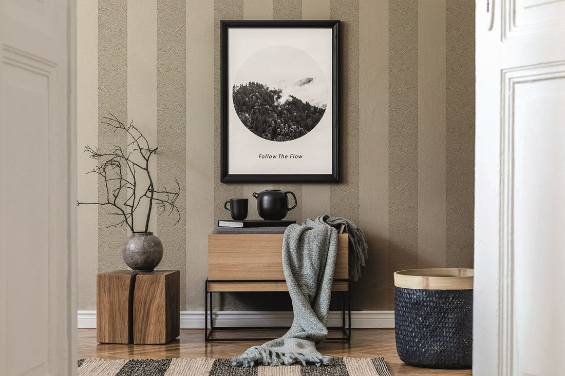Pomalowana stonowana tapeta Patent Decor 9492 z pionowymi pasami przy drewnianym meblu